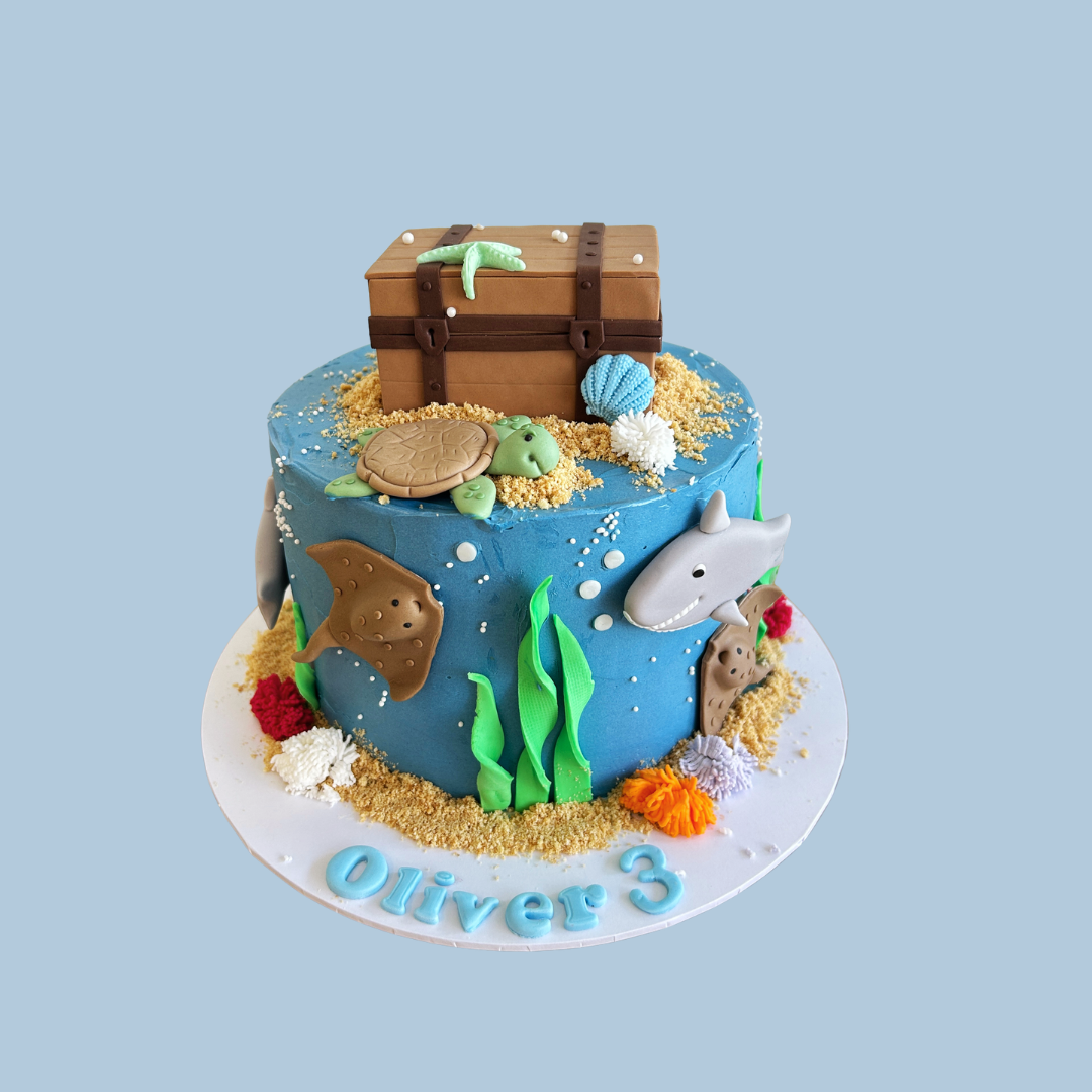 Underwater-themed birthday cake with sea creatures and a treasure chest on a blue background.