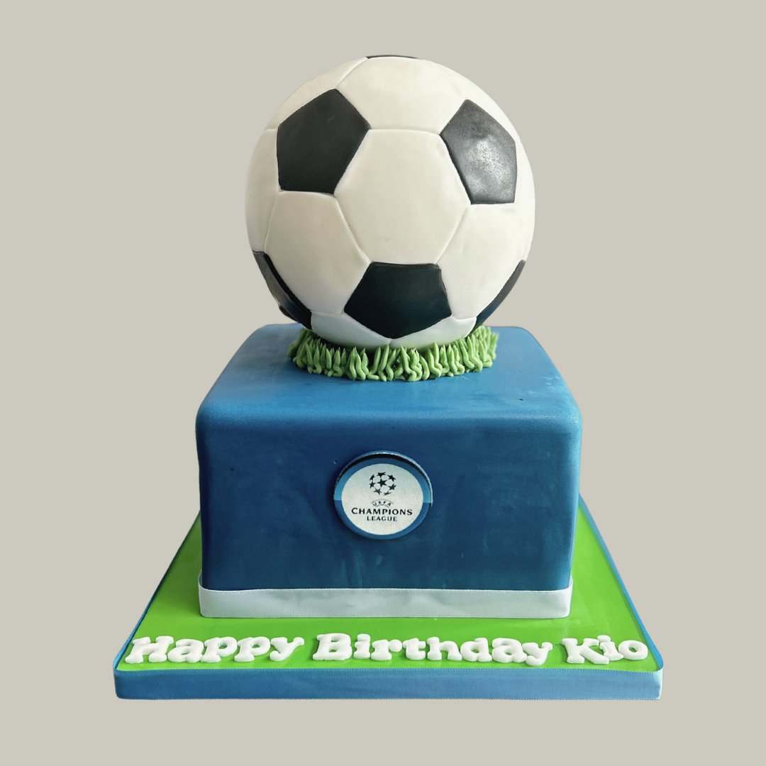 Cake with a soccer ball on top, featuring the Champions League logo.